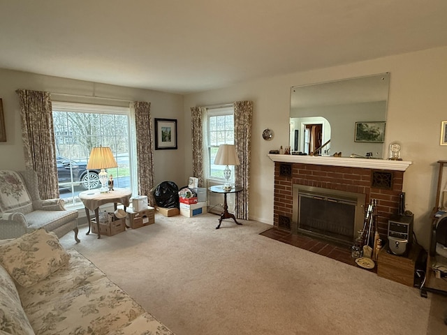 carpeted living room featuring a brick fireplace and baseboards