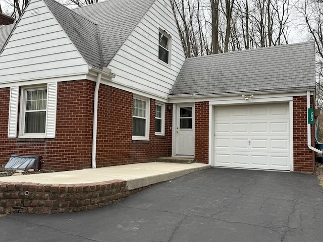 view of side of home with brick siding, aphalt driveway, and a garage