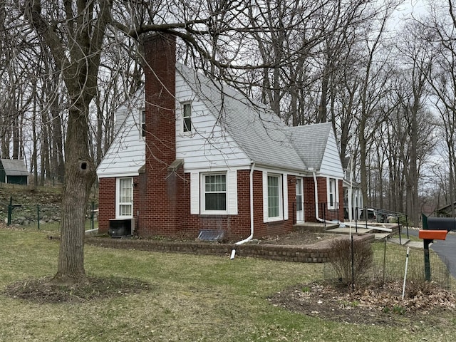 view of property exterior with brick siding, a yard, a chimney, and fence
