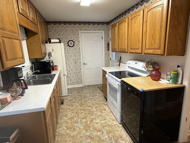 kitchen featuring a sink, wallpapered walls, white appliances, brown cabinetry, and light countertops