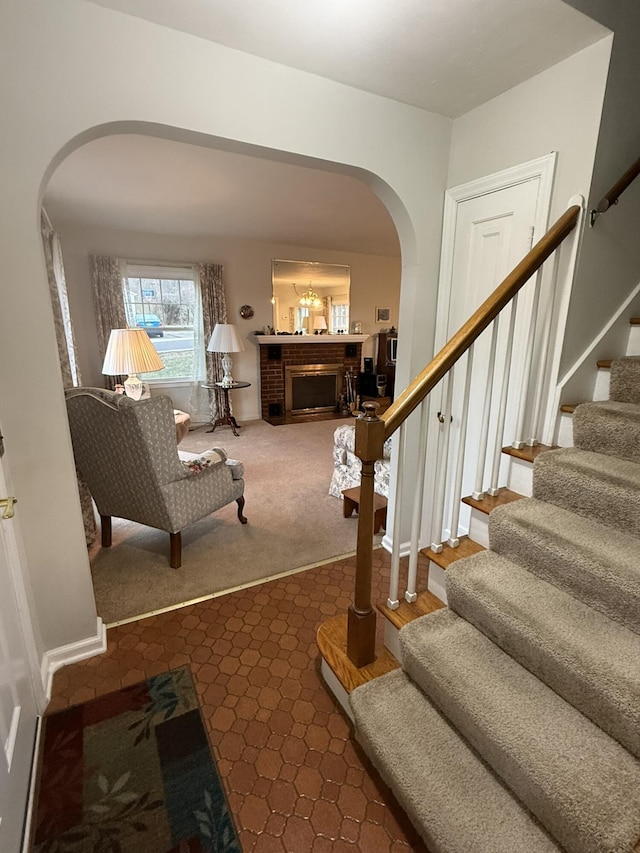 staircase featuring arched walkways, carpet flooring, and a fireplace