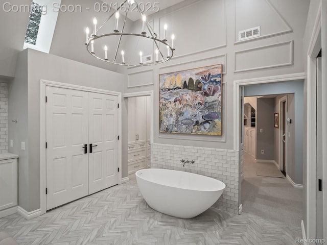 2010 W Valley Rd, Bloomfield Hills, MI 48304 - bathroom with a chandelier, a soaking tub, a high ceiling, and tile walls