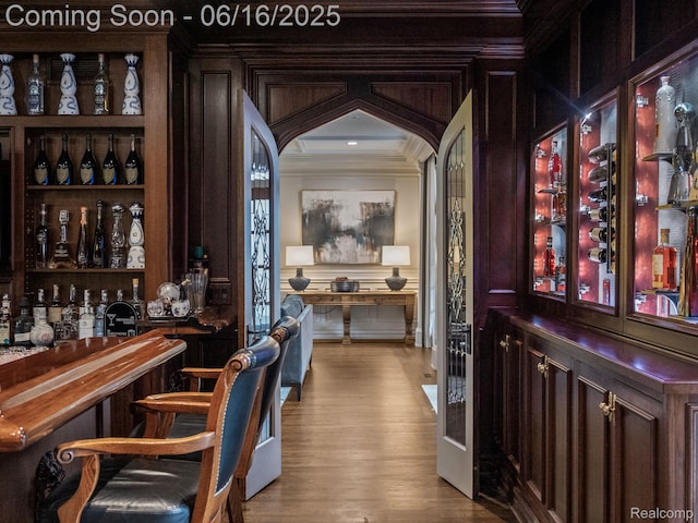 2010 W Valley Rd, Bloomfield Hills, MI 48304 - indoor dry bar featuring crown molding, wood finished floors, and a decorative wall