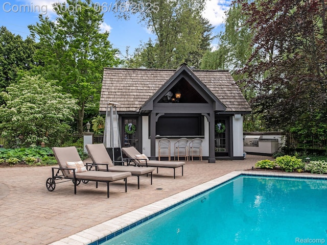 2010 W Valley Rd, Bloomfield Hills, MI 48304 - view of pool with an outdoor kitchen, a patio, an outdoor structure, view of scattered trees, and a storage structure
