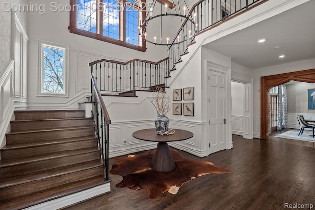 2010 W Valley Rd, Bloomfield Hills, MI 48304 - staircase with a decorative wall, a towering ceiling, a chandelier, wood finished floors, and a wainscoted wall