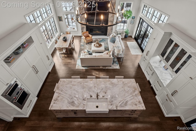 2010 W Valley Rd, Bloomfield Hills, MI 48304 - living room with dark wood finished floors, a high ceiling, a chandelier, and a glass covered fireplace
