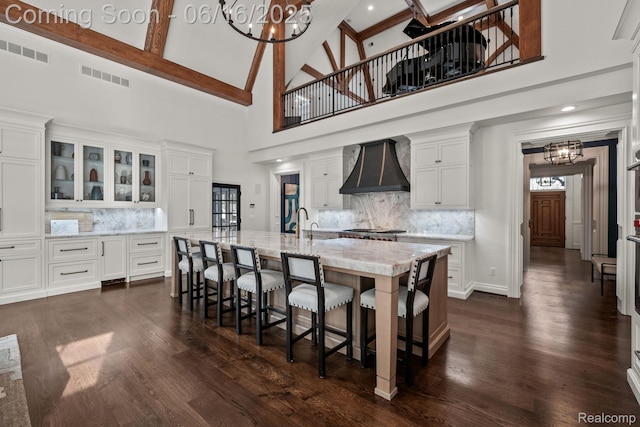 2010 W Valley Rd, Bloomfield Hills, MI 48304 - kitchen with custom range hood, high vaulted ceiling, a chandelier, decorative backsplash, and white cabinetry