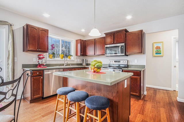 kitchen with a breakfast bar, light wood-type flooring, a center island, and stainless steel appliances
