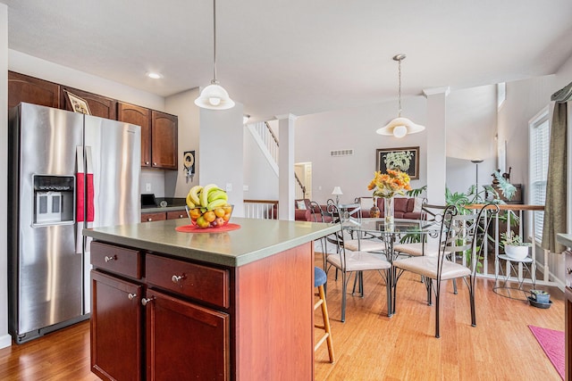 kitchen featuring light wood finished floors, visible vents, stainless steel refrigerator with ice dispenser, and pendant lighting