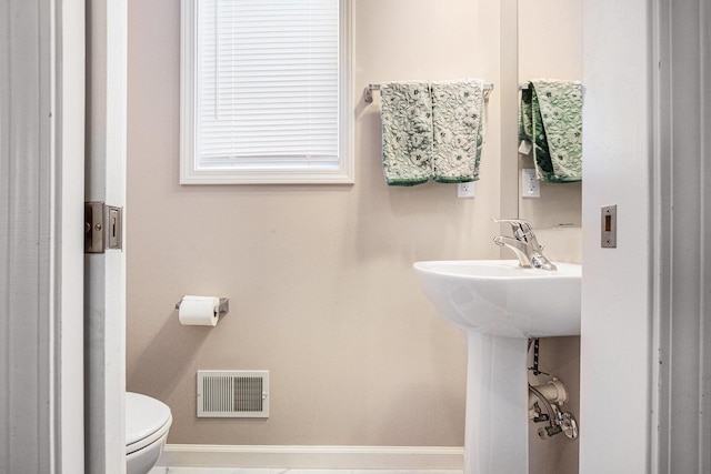 half bath featuring baseboards, visible vents, and toilet
