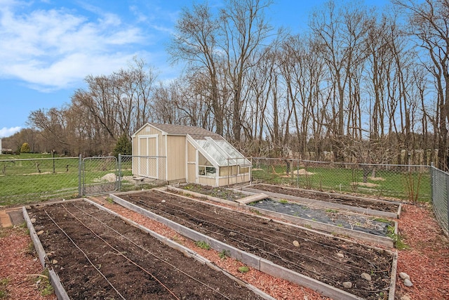 exterior space featuring a vegetable garden, a greenhouse, fence, a yard, and an outbuilding