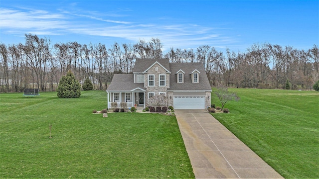 traditional-style house with a front lawn, stone siding, concrete driveway, a garage, and a trampoline