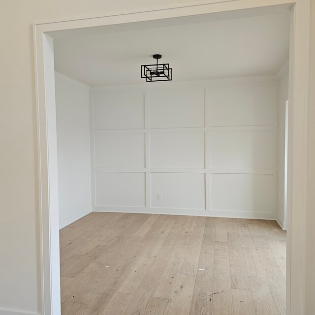 50638 Mistwood Dr, Macomb, MI 48042 - unfurnished dining area with light wood-style floors, crown molding, and a decorative wall