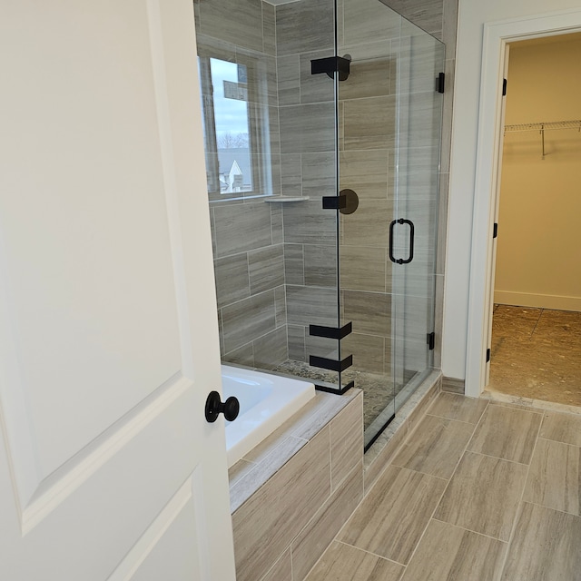 50638 Mistwood Dr, Macomb, MI 48042 - bathroom featuring a stall shower, a garden tub, a walk in closet, and baseboards