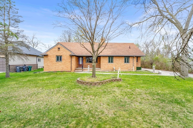 single story home featuring roof with shingles, a front yard, a porch, and brick siding