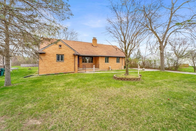back of property featuring a chimney, brick siding, a shingled roof, a porch, and a yard
