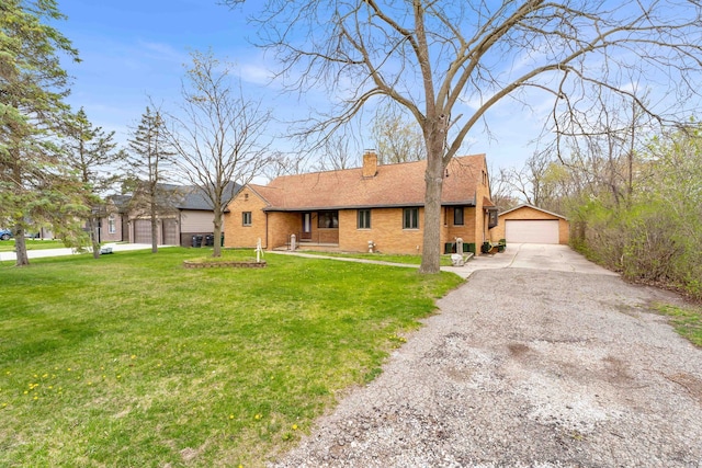 ranch-style house with a detached garage, a chimney, a front yard, and brick siding
