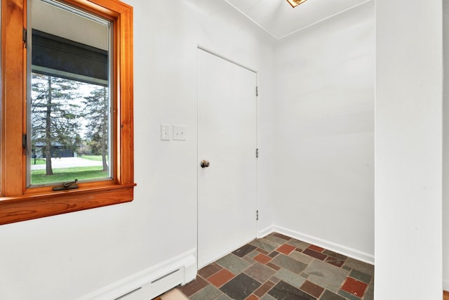 entrance foyer with baseboards, stone finish floor, and baseboard heating