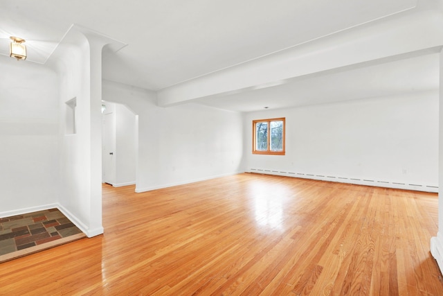 interior space with baseboards, a baseboard heating unit, and light wood-type flooring