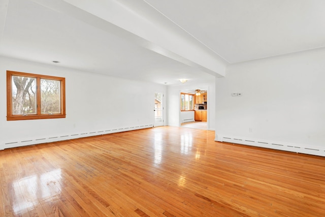unfurnished living room featuring a baseboard heating unit, a wealth of natural light, light wood finished floors, and a baseboard radiator