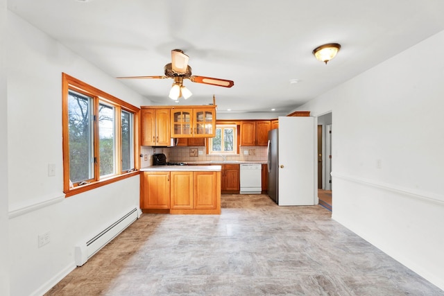 kitchen with a healthy amount of sunlight, freestanding refrigerator, a baseboard heating unit, and dishwasher