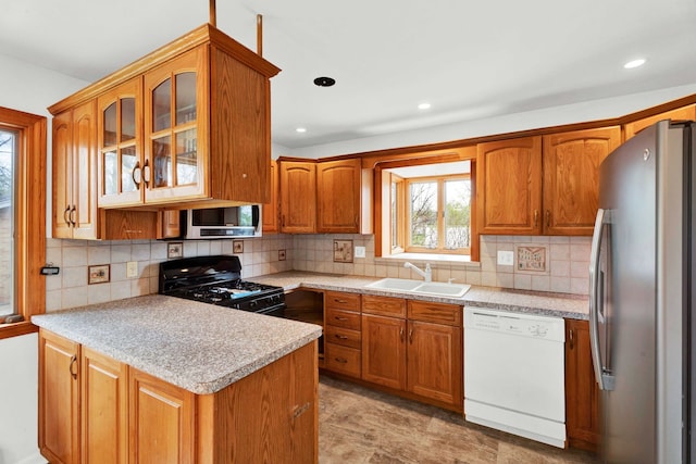 kitchen with a sink, light countertops, stainless steel appliances, and a peninsula