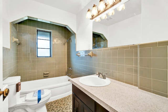 bathroom featuring visible vents, vanity, toilet, tile walls, and washtub / shower combination