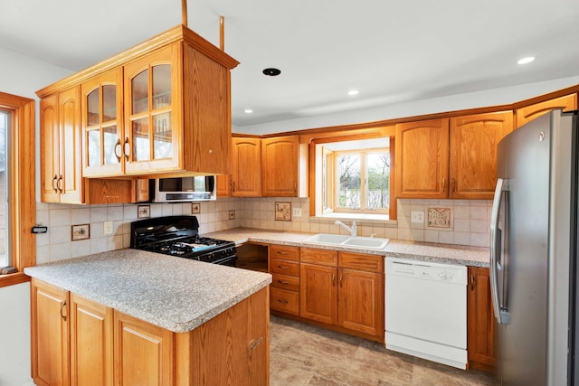 kitchen featuring a sink, appliances with stainless steel finishes, a peninsula, and light countertops