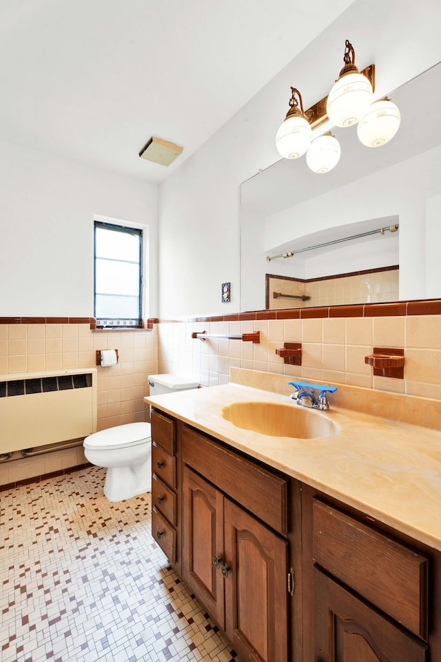 bathroom featuring vanity, radiator, toilet, tile walls, and a wainscoted wall