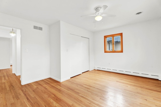 unfurnished bedroom featuring visible vents, baseboards, light wood-style flooring, and a baseboard heating unit