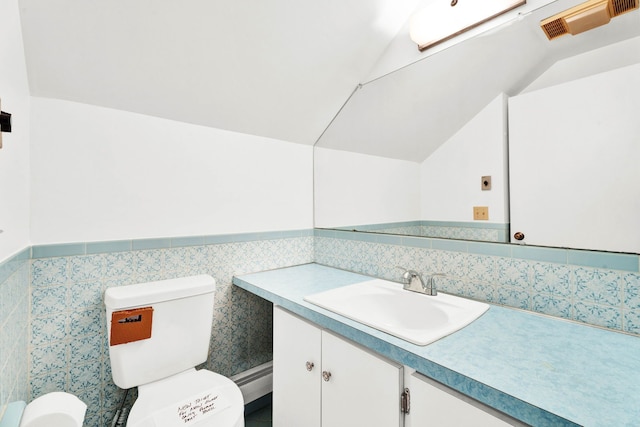 half bath with visible vents, vanity, toilet, tile walls, and vaulted ceiling
