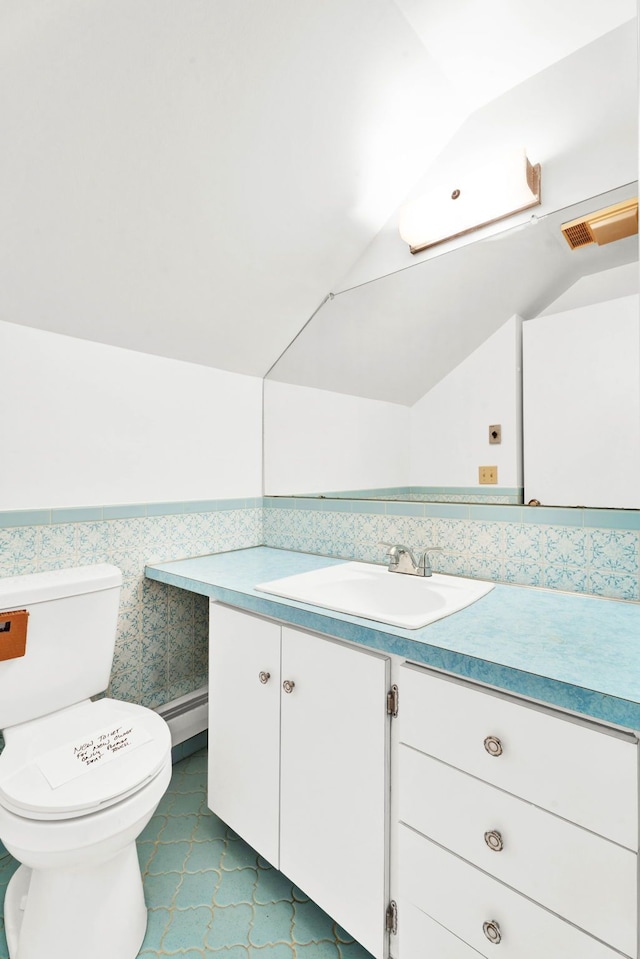 bathroom featuring toilet, vaulted ceiling, baseboard heating, and vanity