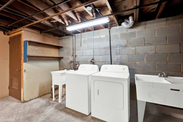 washroom with washing machine and clothes dryer, laundry area, and a sink
