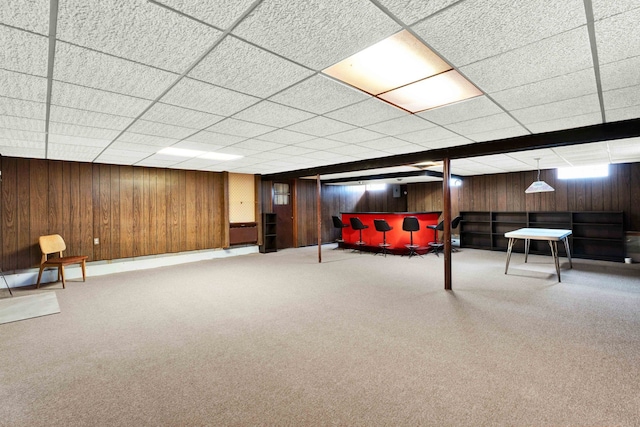 interior space featuring wooden walls, a drop ceiling, and carpet floors