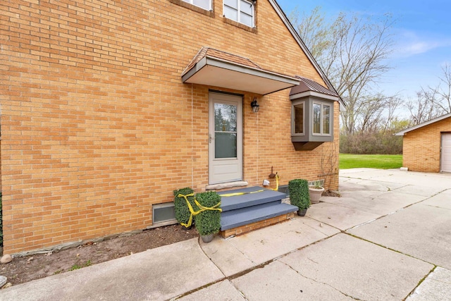 property entrance featuring concrete driveway and brick siding