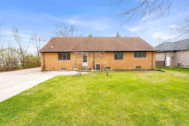 rear view of property featuring entry steps, a shingled roof, a lawn, and brick siding