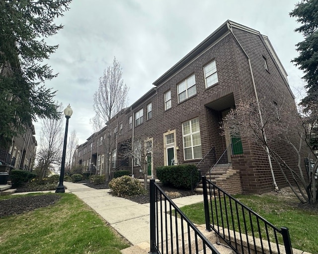 view of home's exterior with brick siding and a lawn