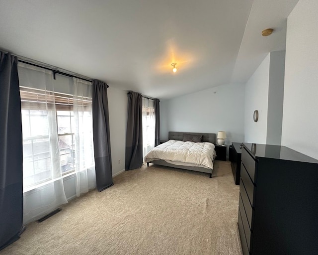 bedroom featuring vaulted ceiling, visible vents, light colored carpet, and multiple windows