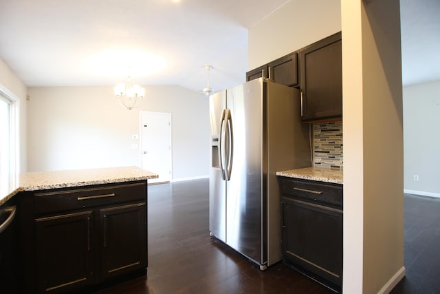 1154 Martin Dr, Frankfort, MI 49635 - kitchen with stainless steel fridge, tasteful backsplash, dark brown cabinetry, light stone counters, and dark wood-type flooring