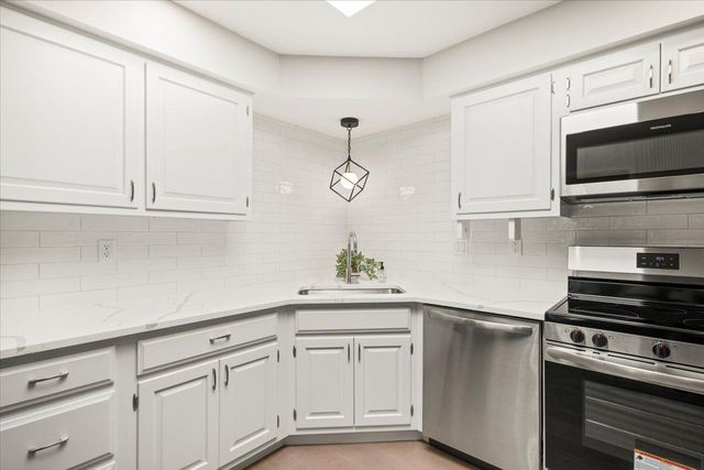 kitchen featuring white cabinets, decorative backsplash, a sink, and appliances with stainless steel finishes
