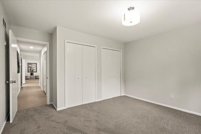 unfurnished bedroom featuring baseboards, multiple closets, and carpet flooring