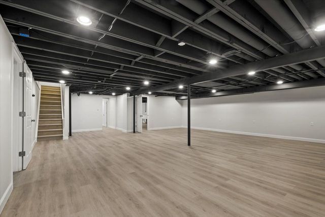 finished basement with light wood-style floors, stairway, and baseboards