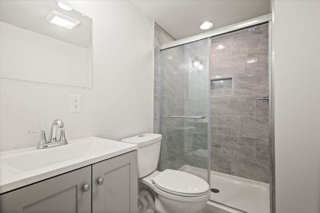 full bathroom featuring toilet, vanity, and a stall shower