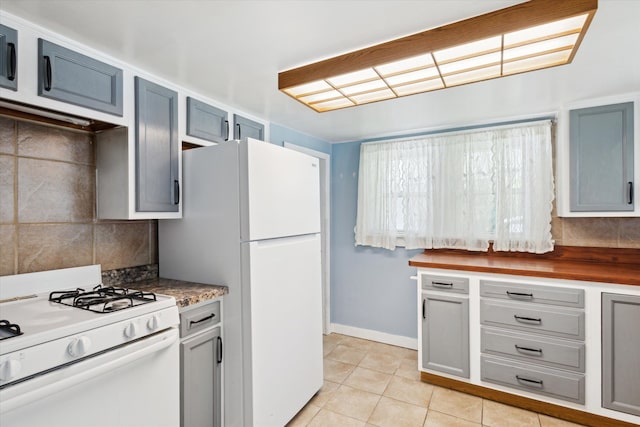 kitchen with white appliances, light tile patterned flooring, tasteful backsplash, baseboards, and gray cabinetry