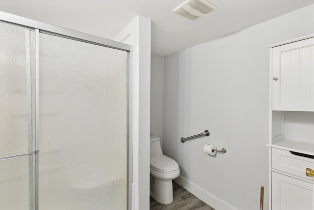 bathroom featuring wood finished floors, a shower stall, toilet, and baseboards