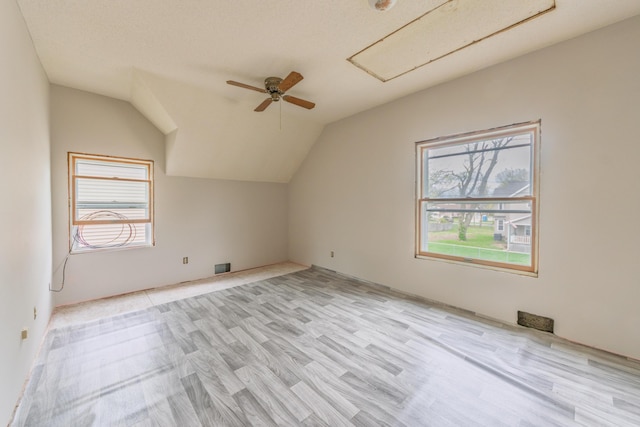 bonus room with vaulted ceiling, visible vents, a ceiling fan, light wood-style floors, and attic access