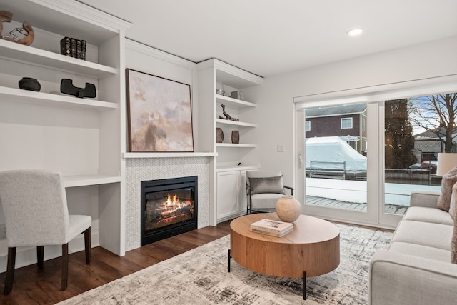 living area featuring recessed lighting, built in features, wood finished floors, and a tiled fireplace