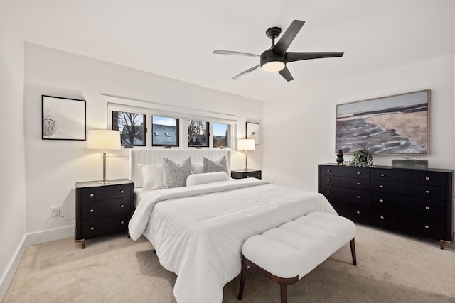 bedroom featuring light carpet, a ceiling fan, and baseboards