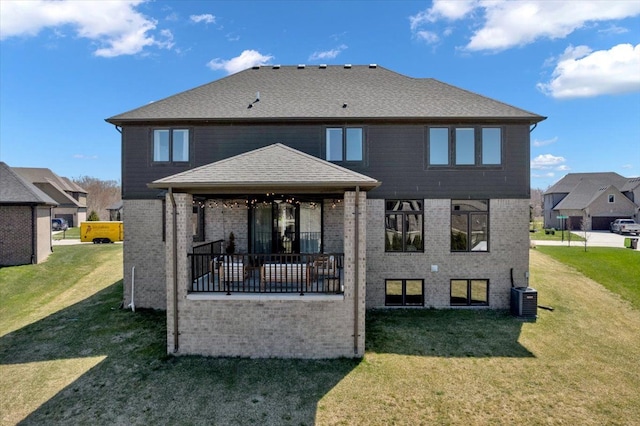 rear view of property with brick siding, a lawn, and central AC