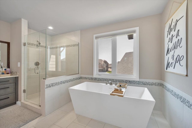 full bathroom with a shower stall, tile walls, a wainscoted wall, a freestanding bath, and tile patterned flooring